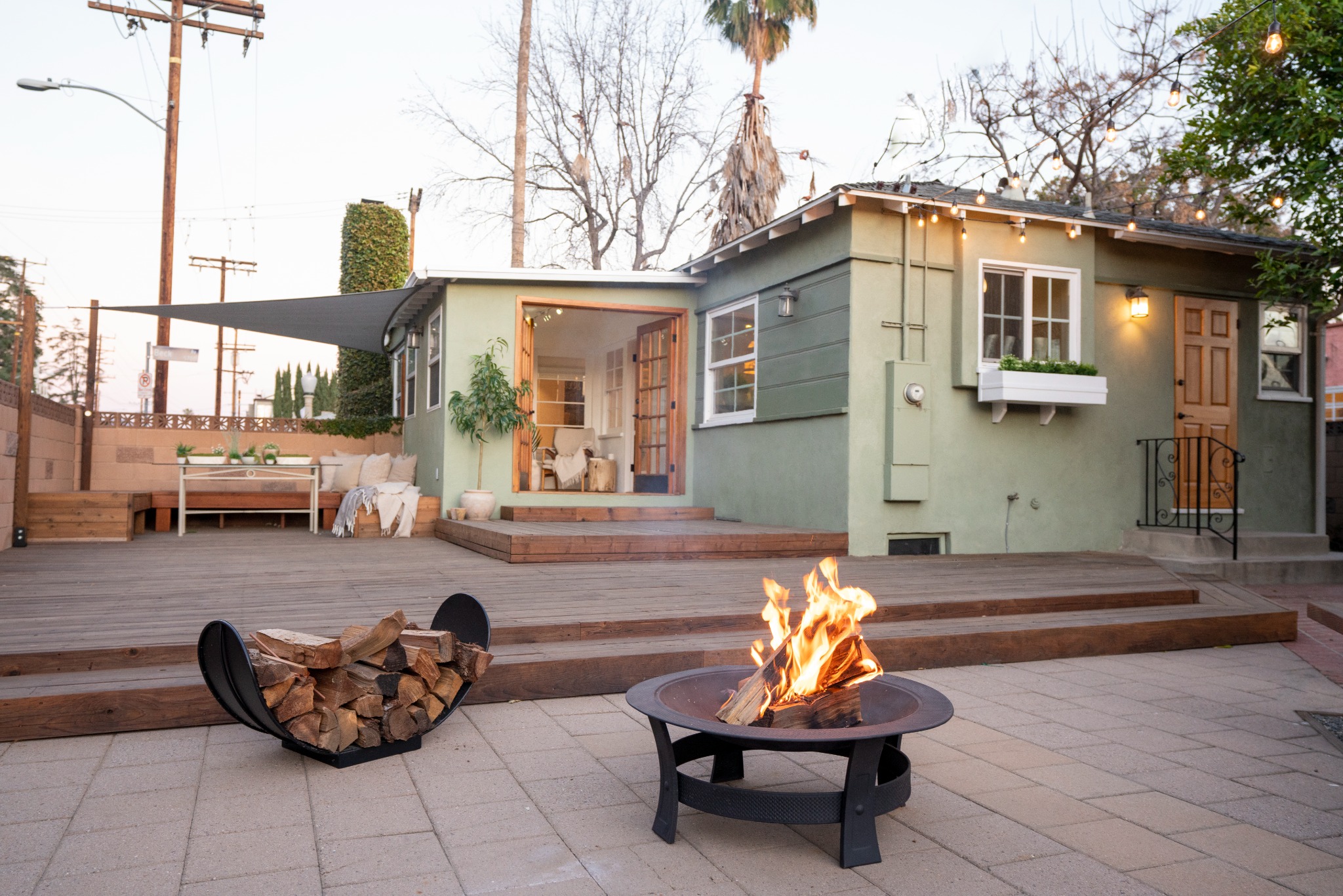 Backyard at dusk at Amani Residence, North Hollywood, with fire pit and string lights