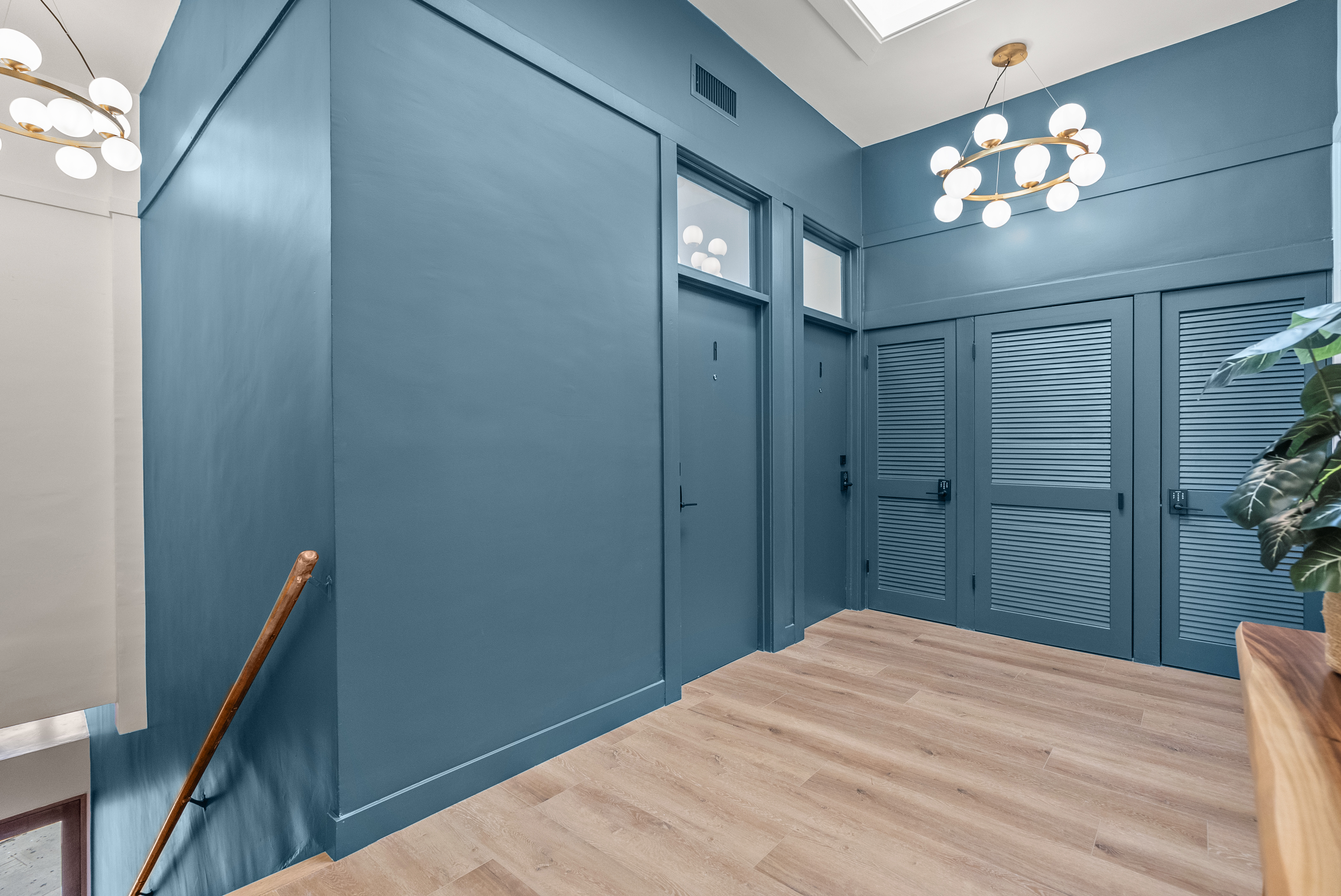 Dramatic blue entry foyer with globe chandeliers at Playa Lofts, an Earendel portfolio property