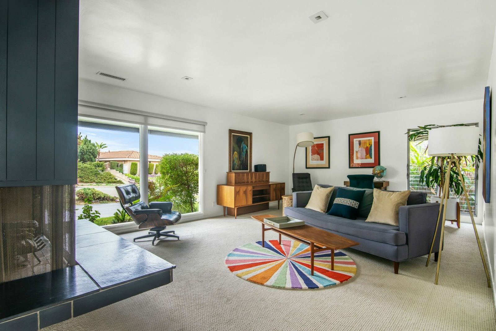 Mid-century living room with a walnut credenza and floor-to-ceiling windows in a furnished home