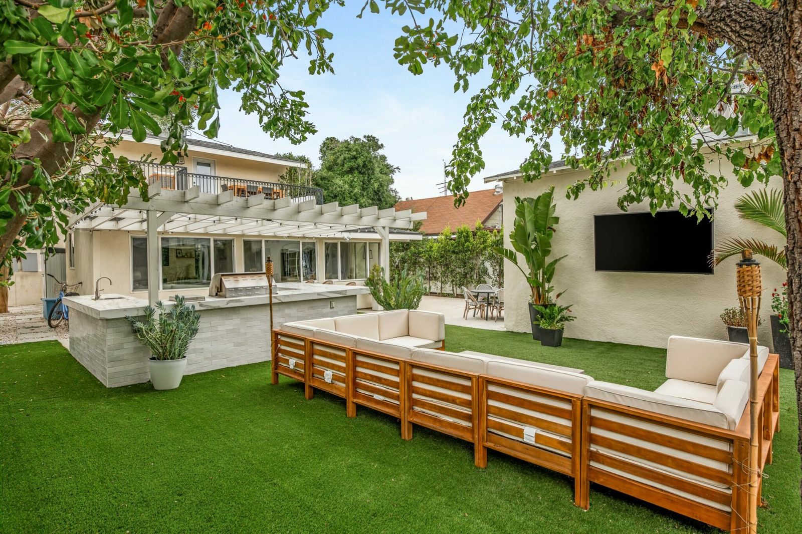 Backyard with outdoor kitchen, lawn, and lounge seating at a furnished Earendel property