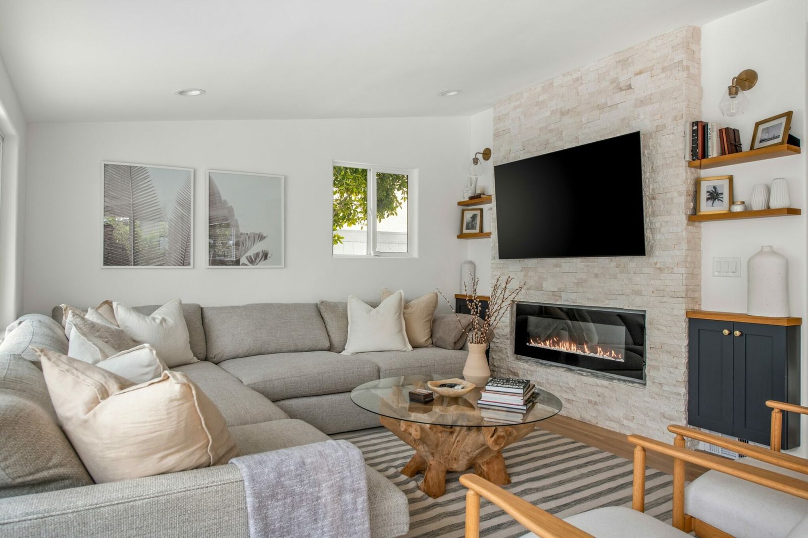 Family room with a stacked stone linear fireplace and a linen sectional in a furnished residence