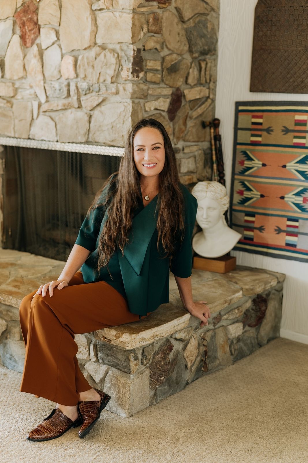 Veronica Garreton, founder of Earendel Management, seated by a stone fireplace in a Los Angeles home