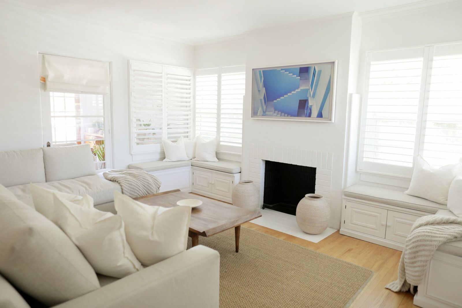 Bright white living room with window seats and plantation shutters in a furnished Los Angeles home