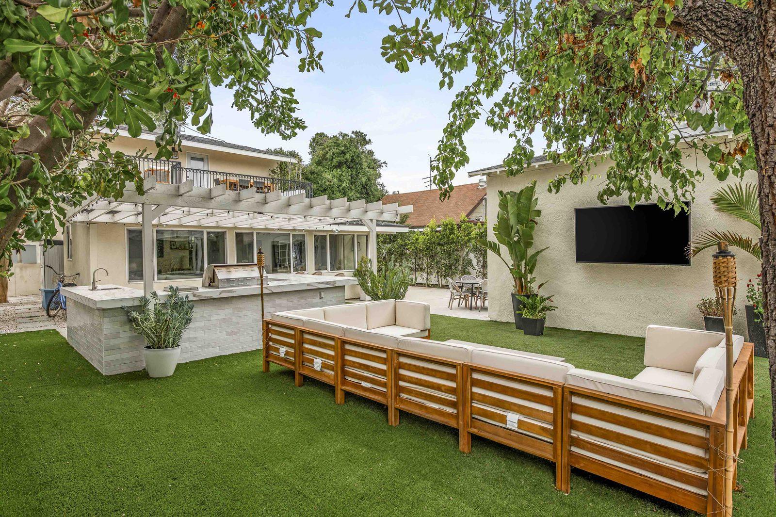 Backyard lounge with pergola, fire pit, and outdoor TV at Rose House, a furnished 4-bedroom home in Magnolia Park, Burbank